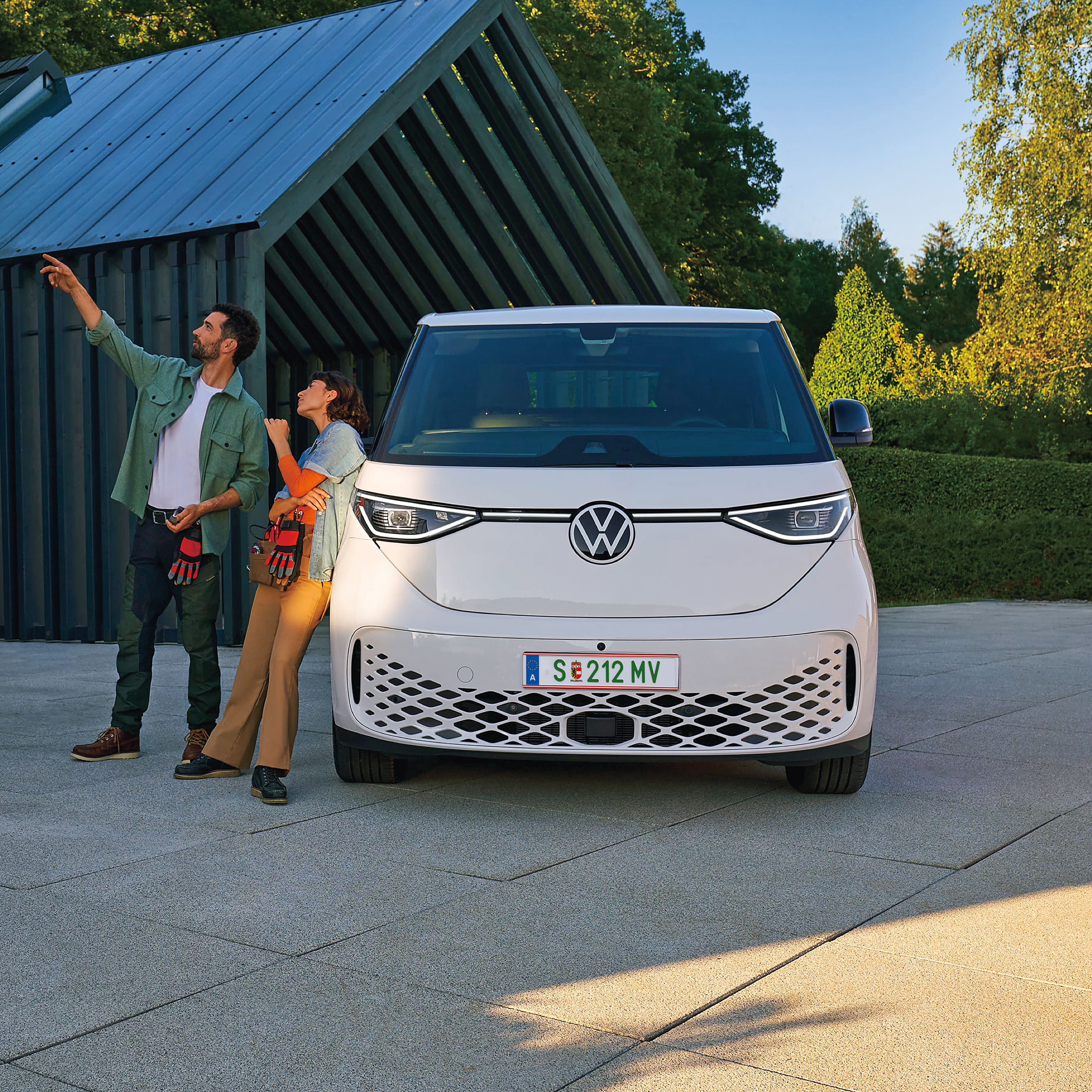 Heck des neuen VW T7 Multivan Style ist zu sehen und ein Mann und eine Frau spazieren vorbei