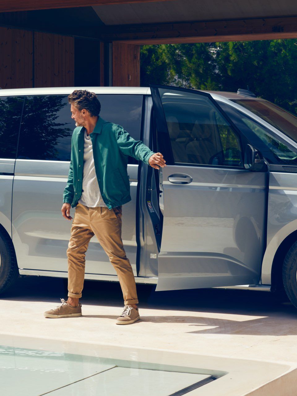 Zwei Männer stehen mit Gepäck neben dem neuen VW Multivan T7 2021.