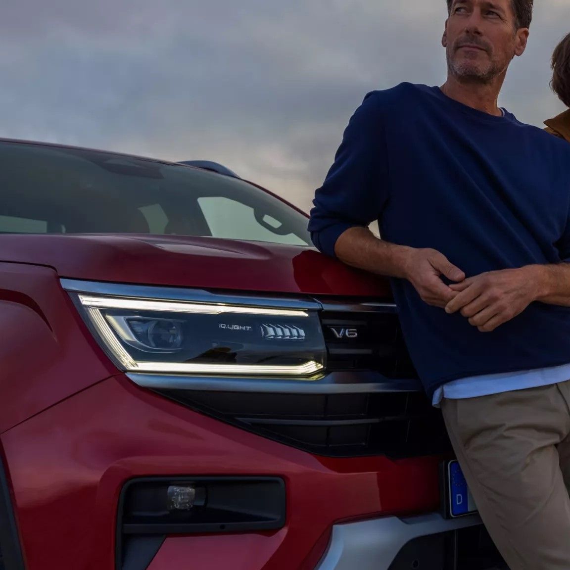 Ein Familienvater öffnet die Heckklappe eines bronzenen VW Caddy.