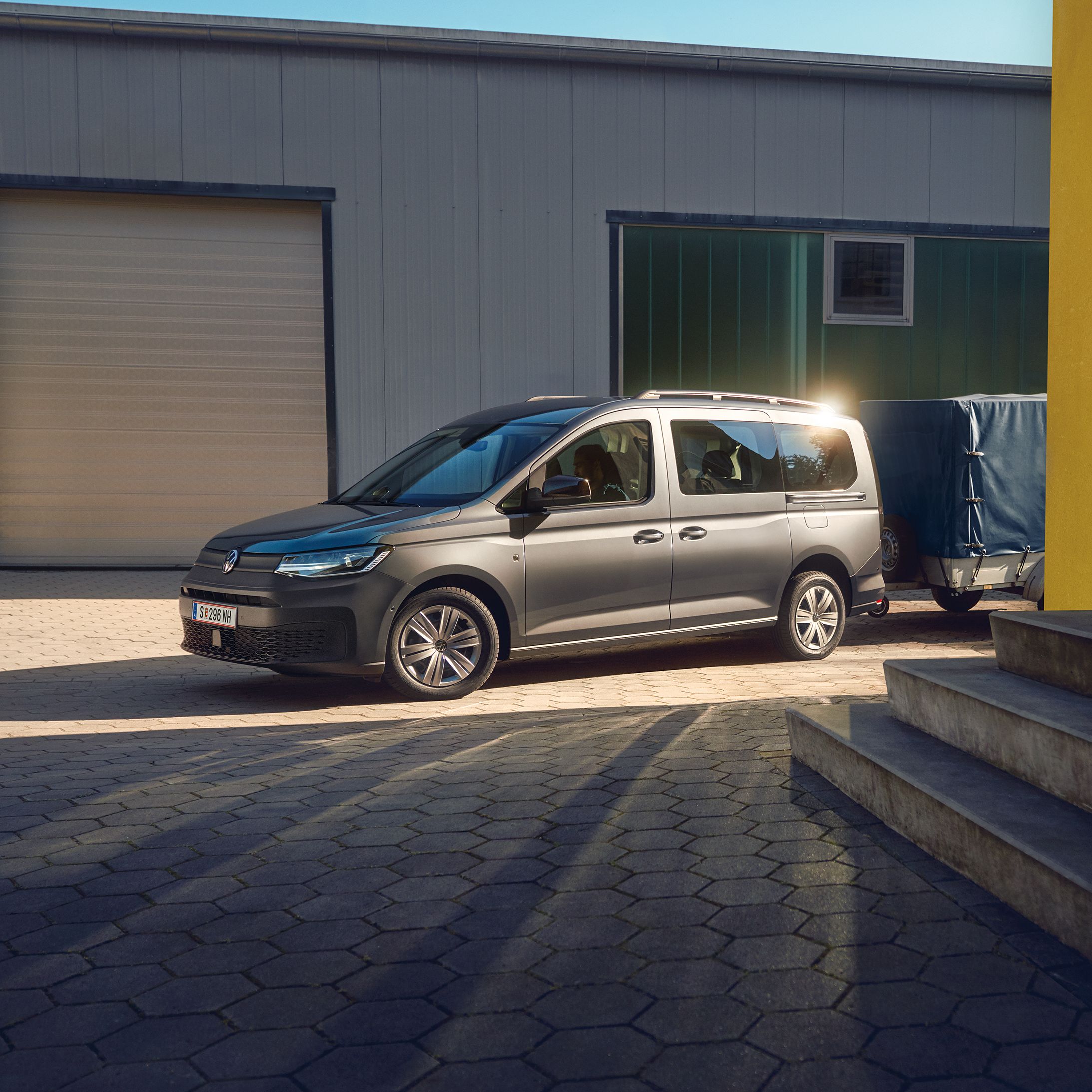 Ein weißer Caddy Kastenwagen fährt dynamisch durch eine belebte Stadt.
