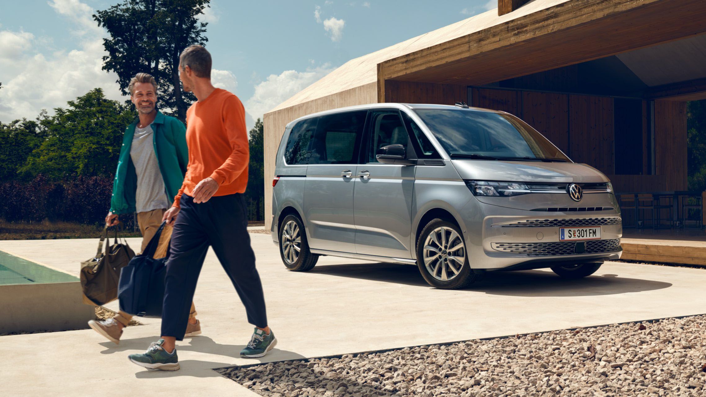 VW Multivan in silber parkt und 2 Männer bewegen sich von ihm fort