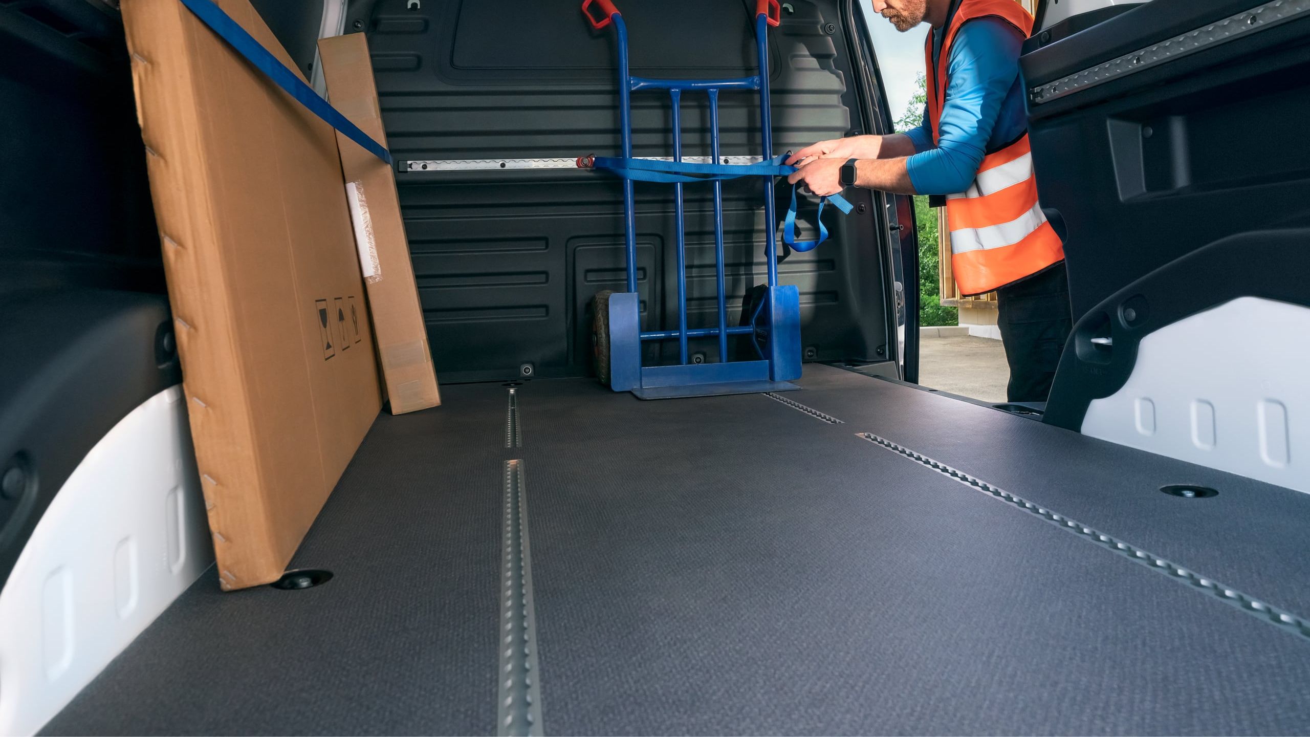 Eine Sackkarre wird im Laderaum eines ID. Buzz Cargo mit Hilfe des Schienensystems für den Transport gesichert
