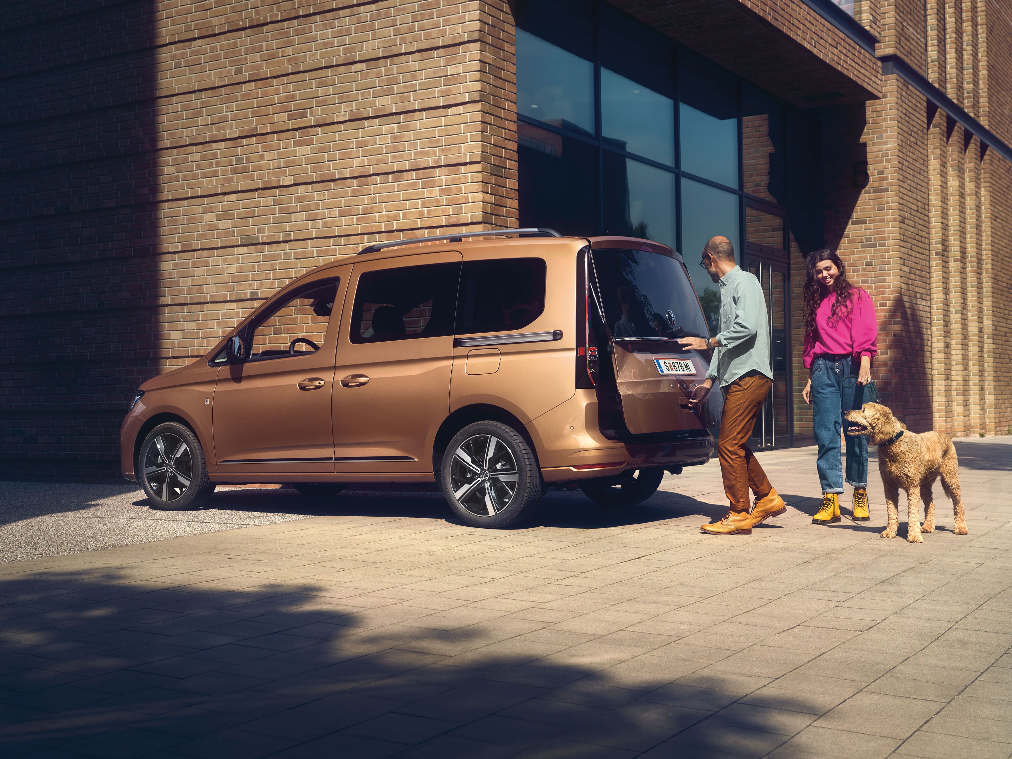 Ein Mann öffnet die Heckklappe mit Fenster eines VW Caddy.
