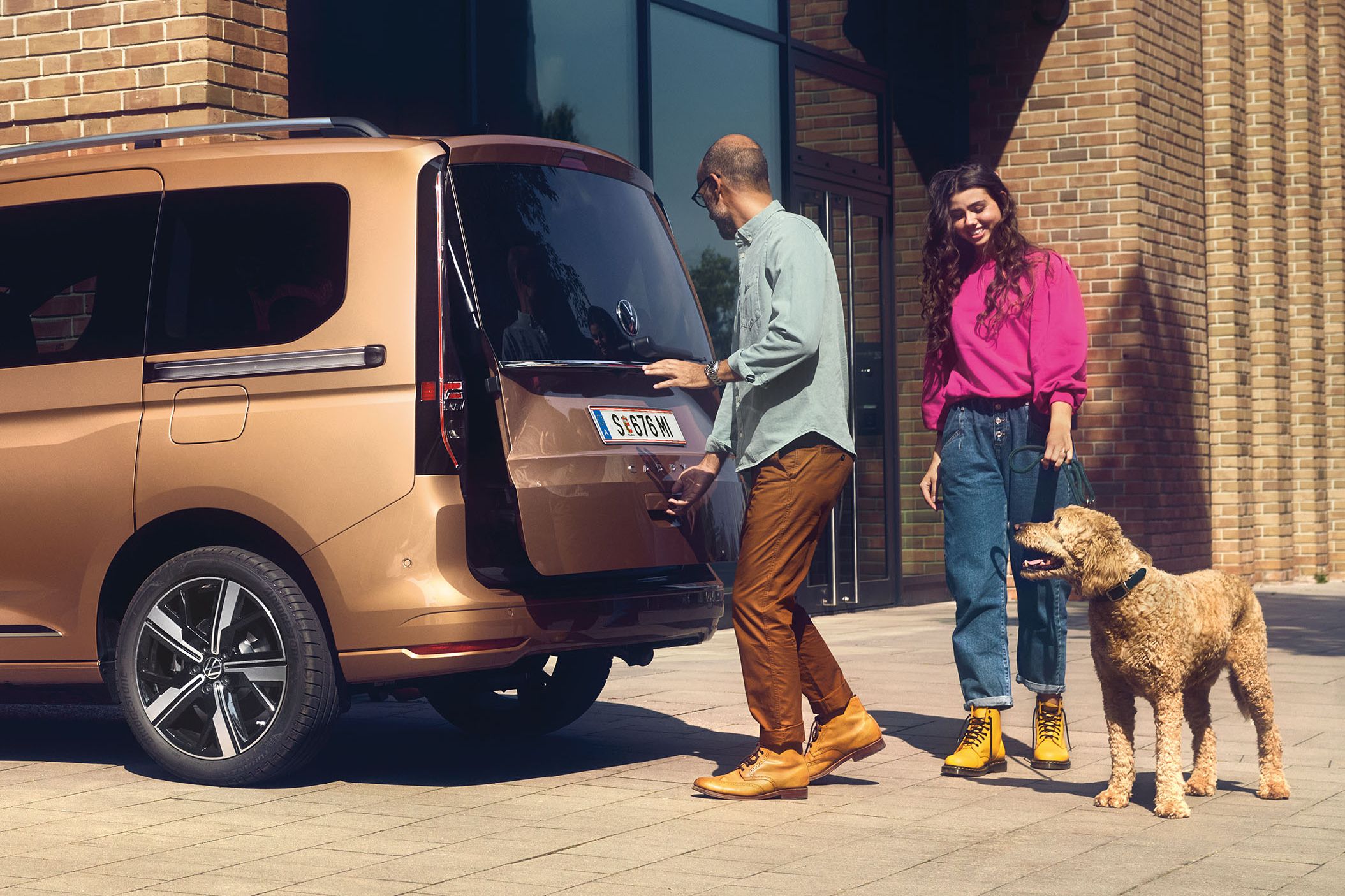 Ein Mann öffnet die Heckklappe mit Fenster eines VW Caddy.