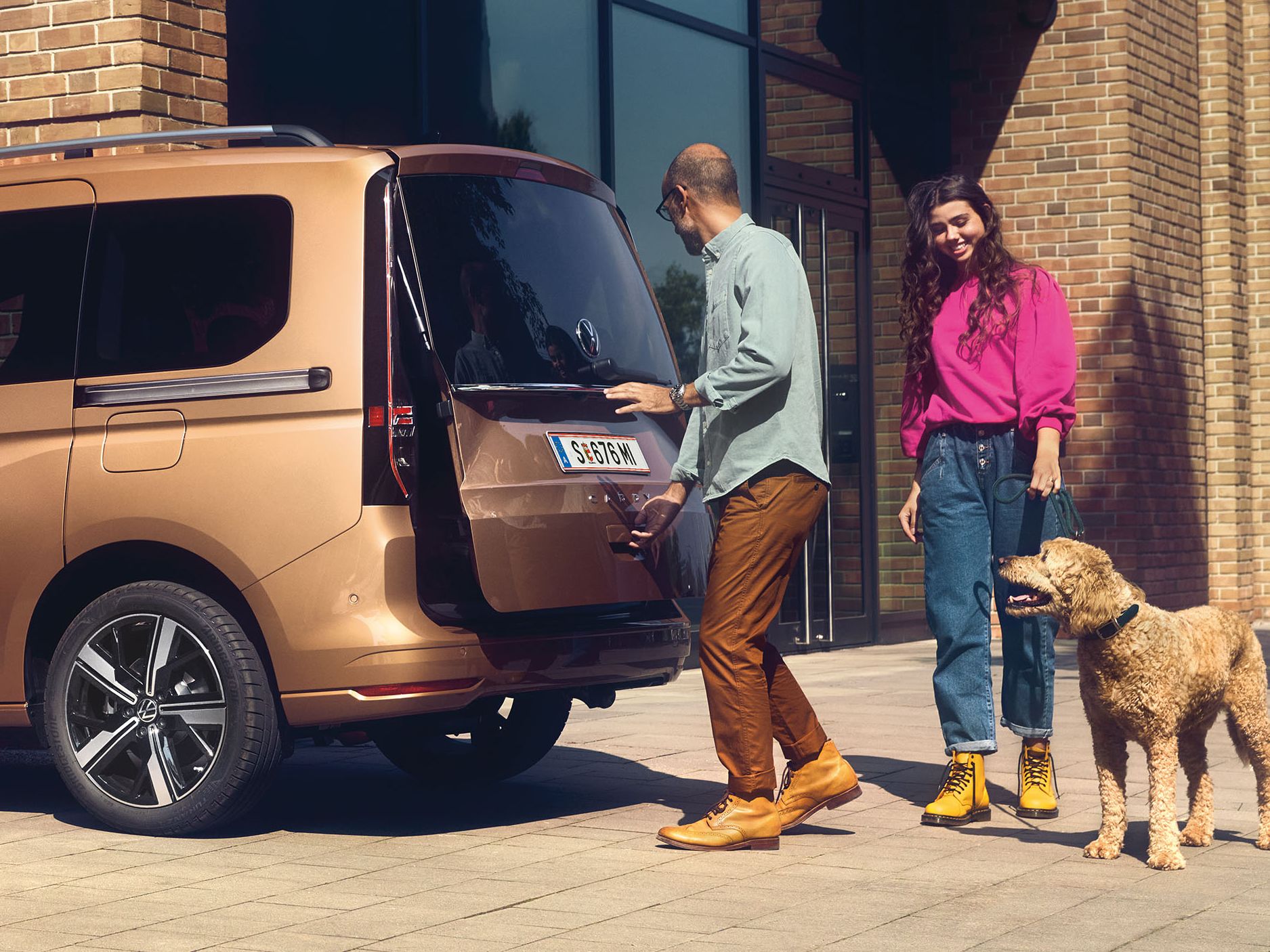 Ein Mann öffnet die Heckklappe mit Fenster eines VW Caddy.