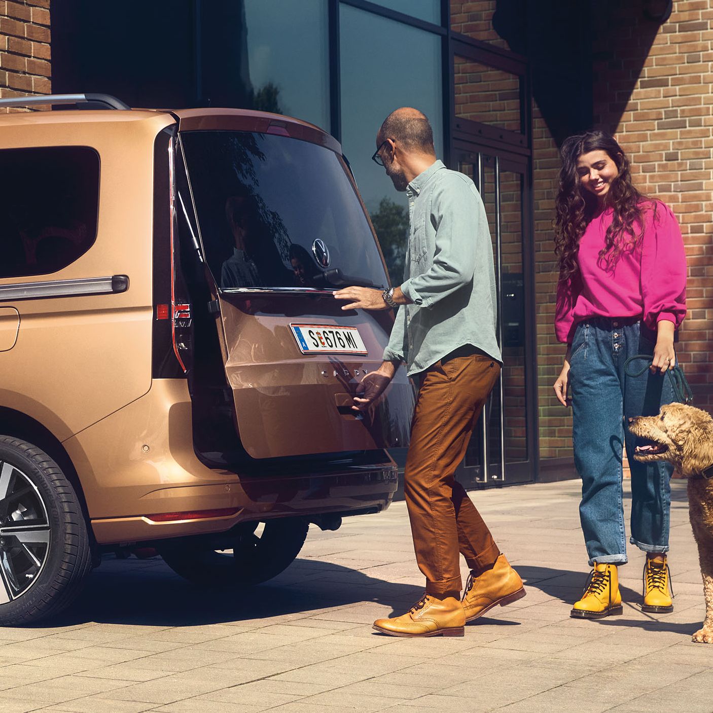 Ein Mann öffnet die Heckklappe mit Fenster eines VW Caddy.