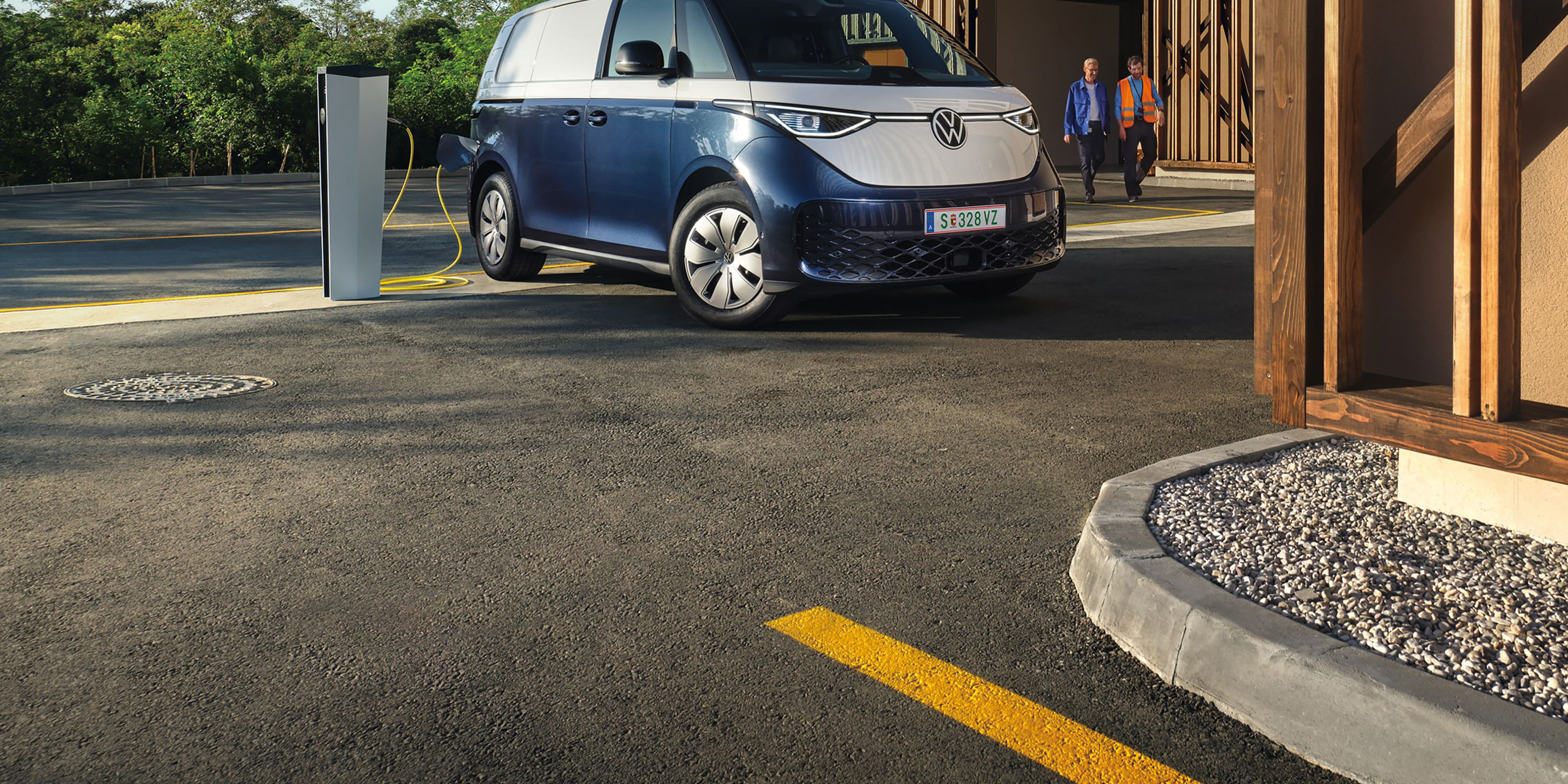VW ID. Buzz și ID. Buzz Cargo într-o curte interioară, în fața unui perete de culoare portocalie