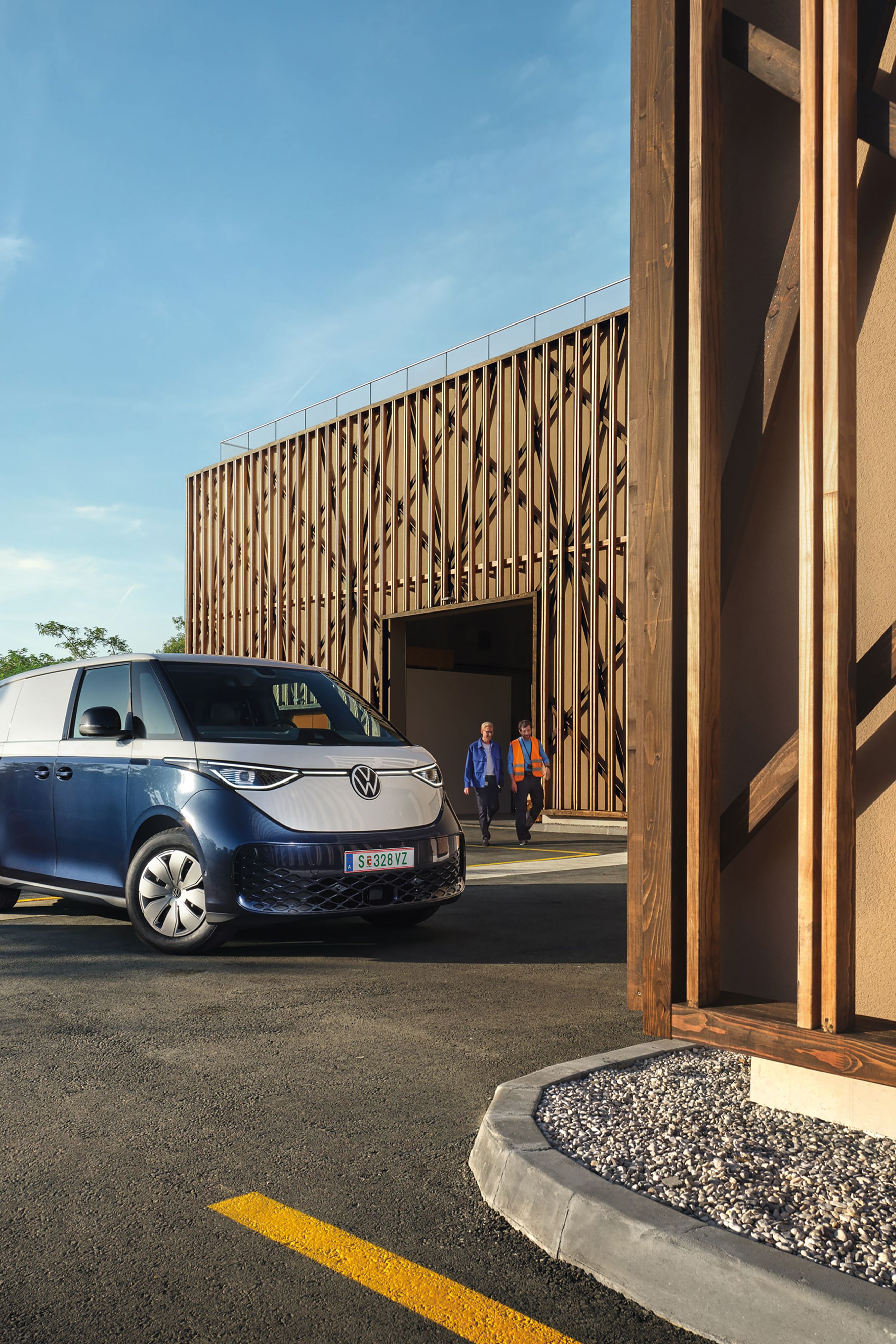 VW ID. Buzz și ID. Buzz Cargo într-o curte interioară, în fața unui perete de culoare portocalie