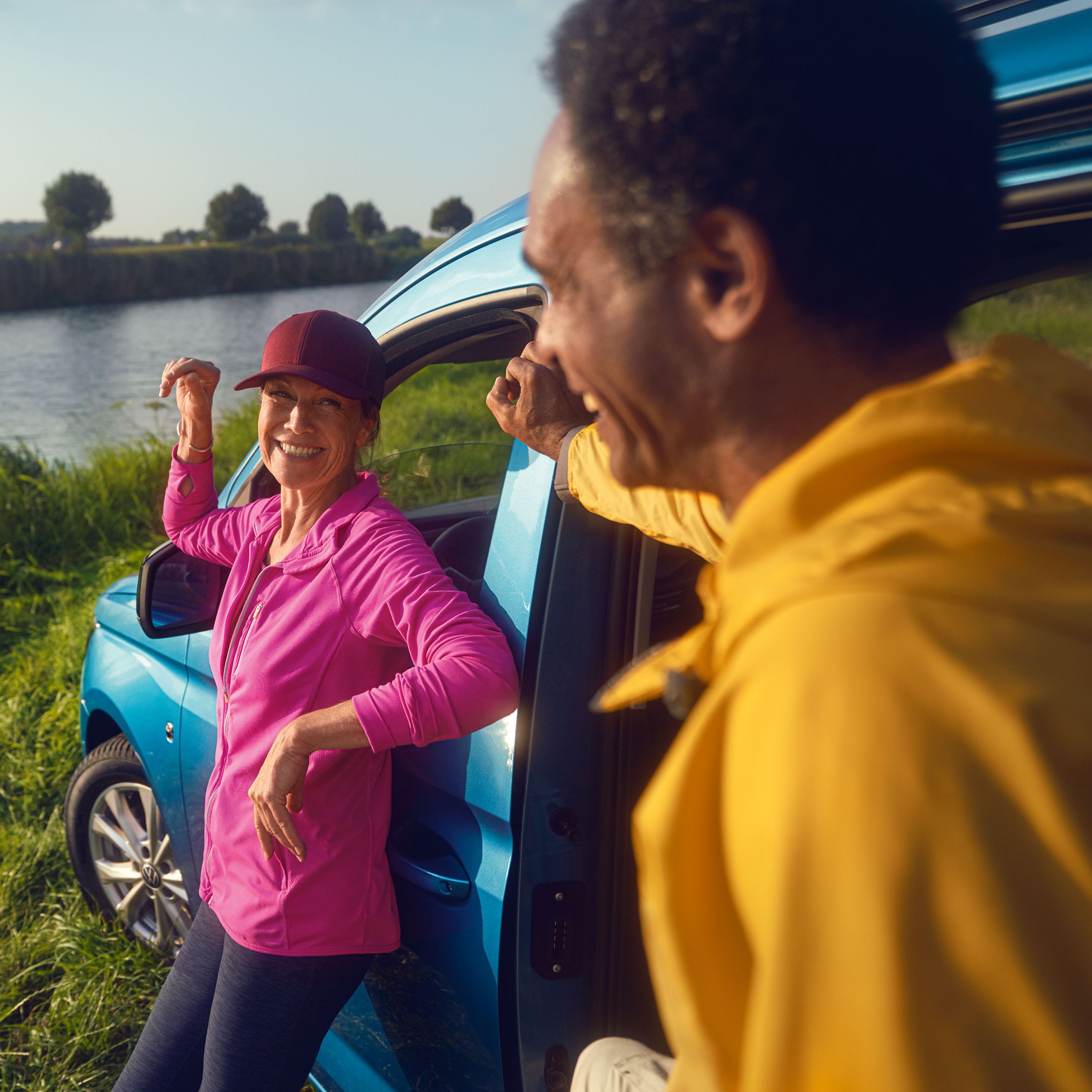Frau lehnt an blauem VW Golf R Motorhaube