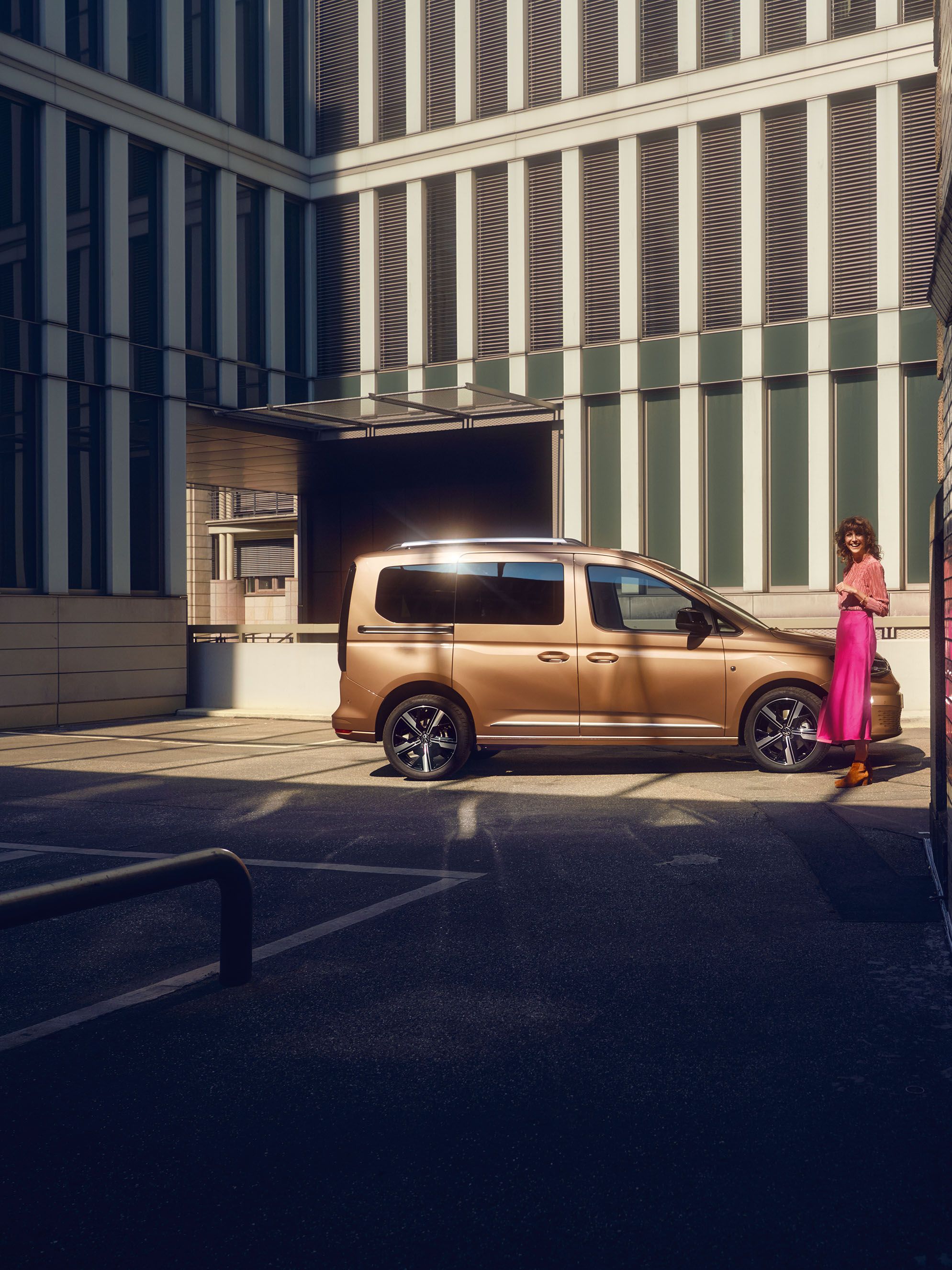 Eine Frau steht neben einem VW Caddy der von der Seite zu sehen ist.