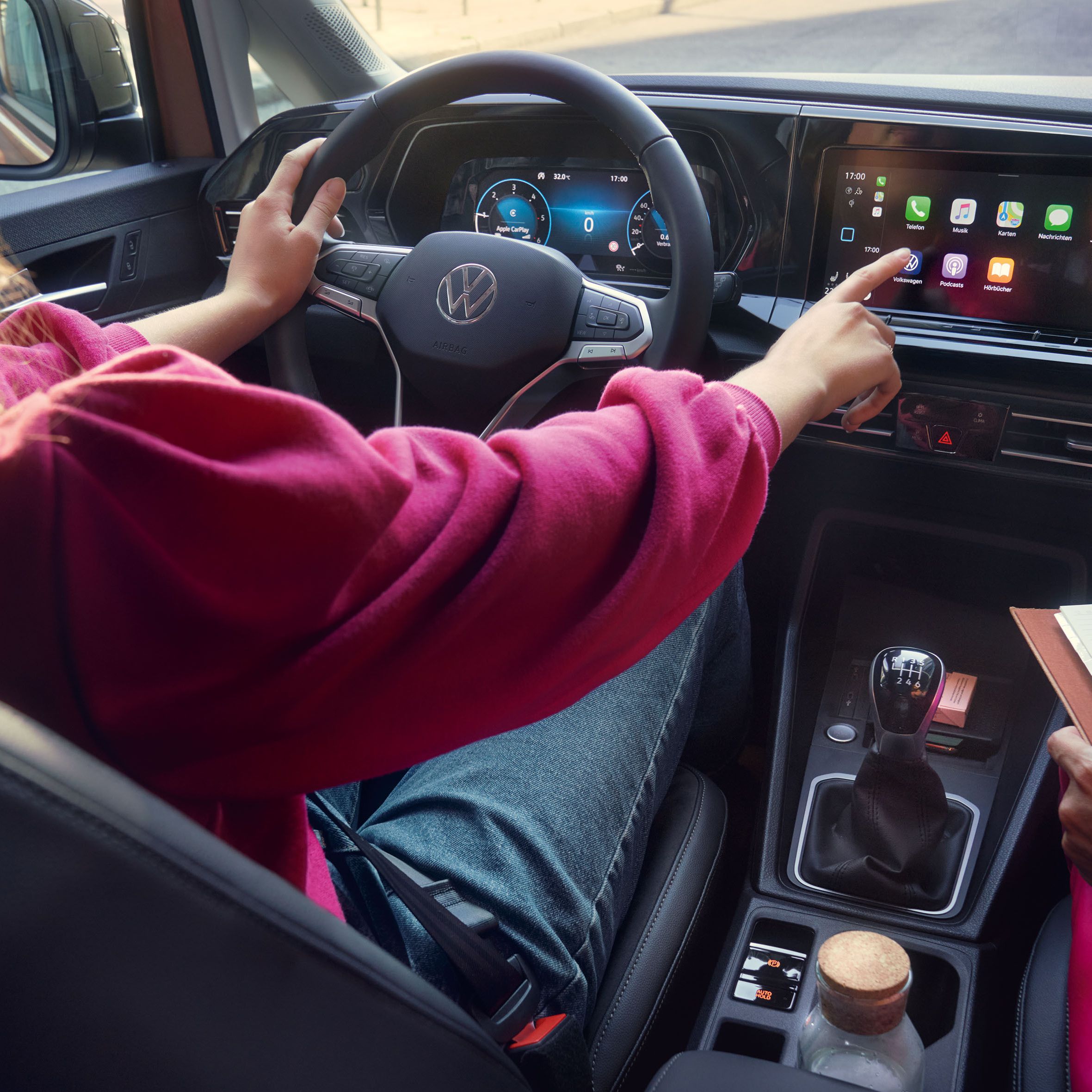 Frau sitzt im VW Caddy California und bedient das Display. 